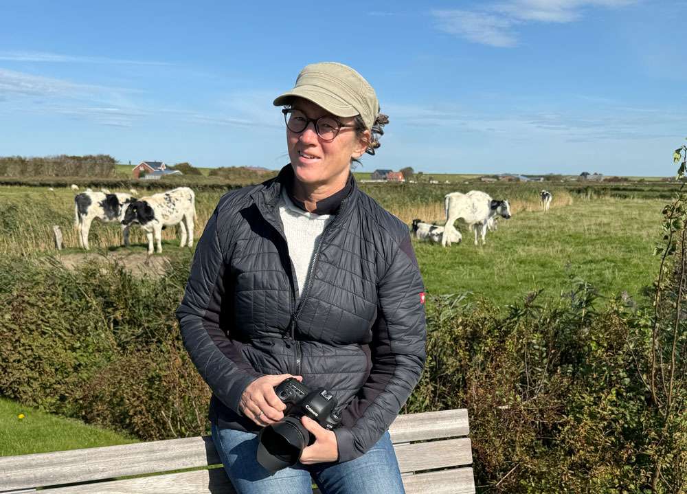 Ines Preißer - Inhaber geführte Webagentur in Nordfriesland - sitzend auf der Bank, Natur genießend, mit der Kamera in der Hand